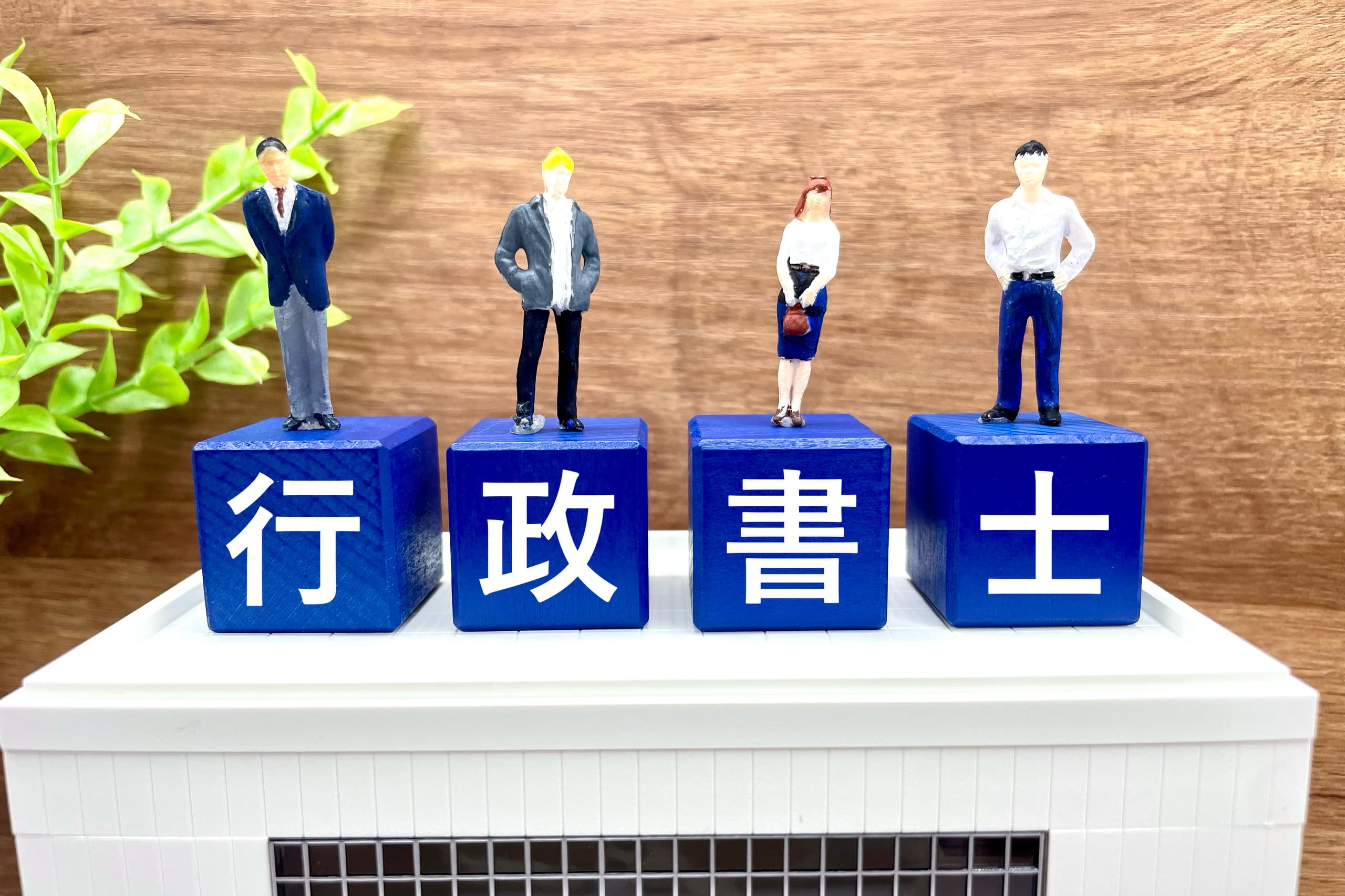 行政書士の文字と4体のビジネスフィギュアによる事務所トップページ用イメージ画像